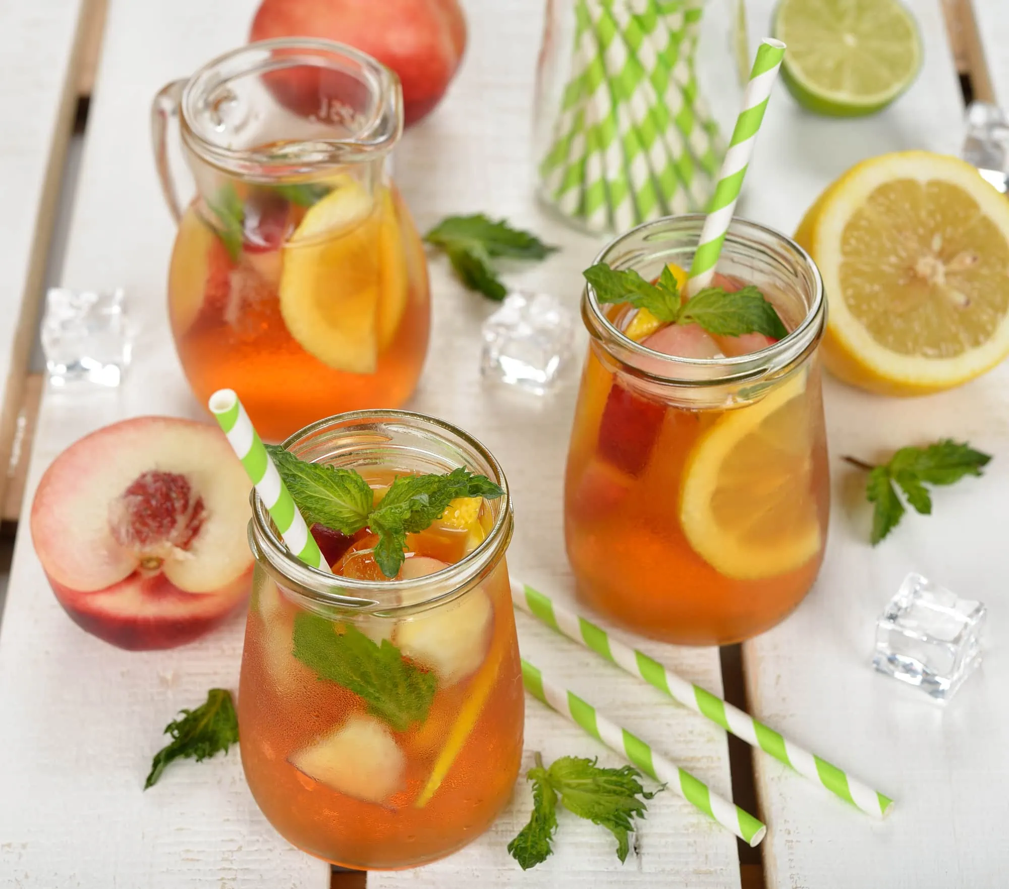 Ice tea with lemon, peach and mint on a white background